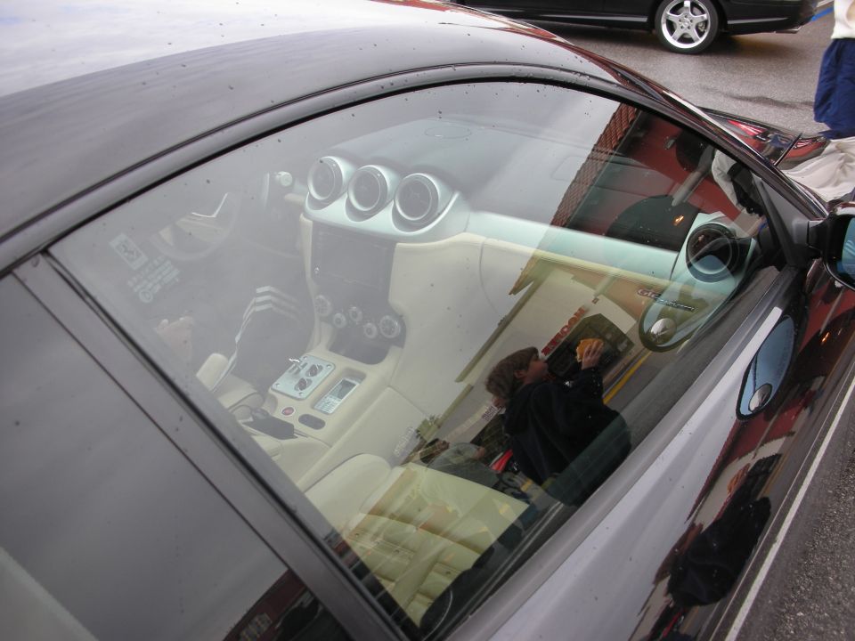 View through a car side window into a tan leather interior with gauges