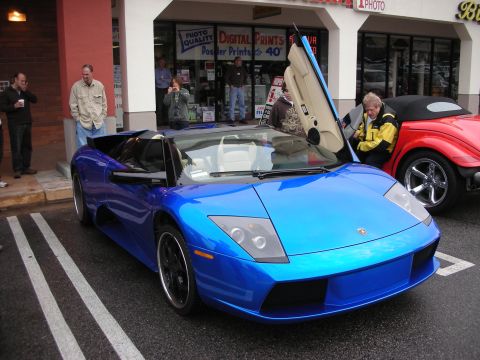 1998 Ford Crown Victoria - blue Lamborghini Murcielago roadster parked with a scissor door open in front of a photo shop.