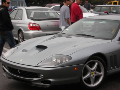 1998 Ford Crown Victoria - gray Ferrari coupe shown from the front three-quarter, with a silver Subaru sedan behind it.
