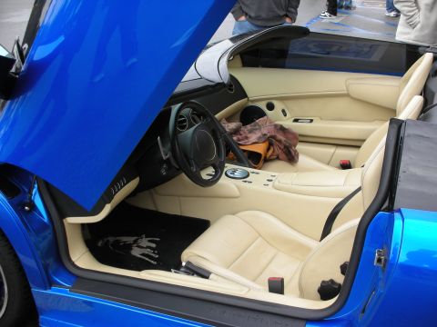 1998 Ford Crown Victoria - tan-leather cockpit of a blue Lamborghini, door raised showing the Lamborghini-marked sill.