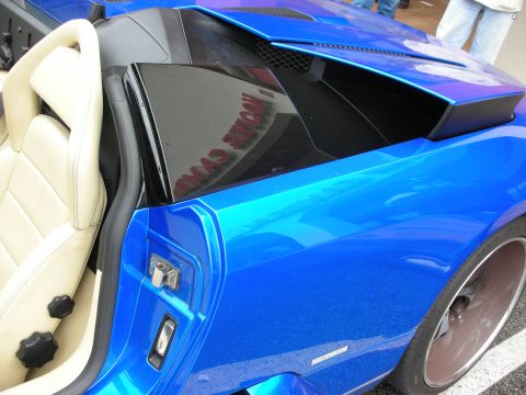 1998 Ford Crown Victoria - blue Lamborghini's rear quarter air intake scoop beside a tan leather seat.