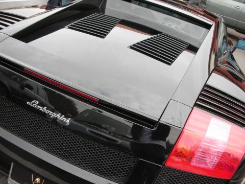 1998 Ford Crown Victoria - black Lamborghini Gallardo's rear deck showing the Lamborghini badge, engine louvers and taillight.