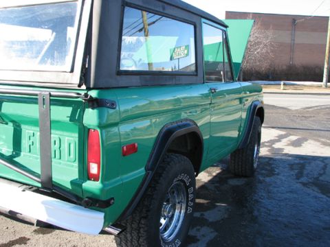 1975 Ford Bronco - This green Ford Bronco is shown from the rear quarter with its hood open, revealing a sign in the window.
