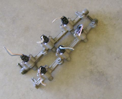 1994 Mazda MX-3 - Fuel injector rail with wiring, likely from a car engine, on a concrete floor.