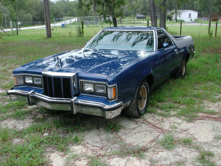 Blue late-1970s Ford Ranchero car-pickup parked on grass, front three-quarter view