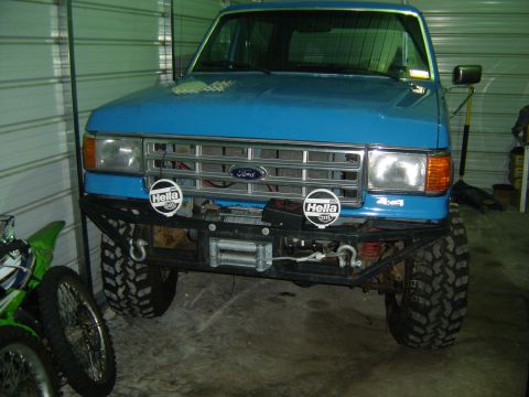 1988 Ford Bronco - This blue Ford truck features a winch and auxiliary lights on its custom front bumper.