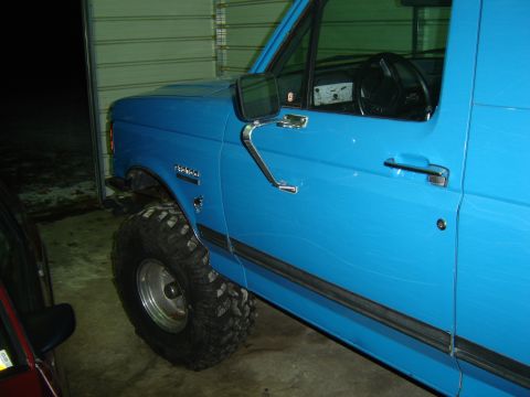 1988 Ford Bronco - This blue 1988 Ford Bronco features large off-road tires and a side profile view.