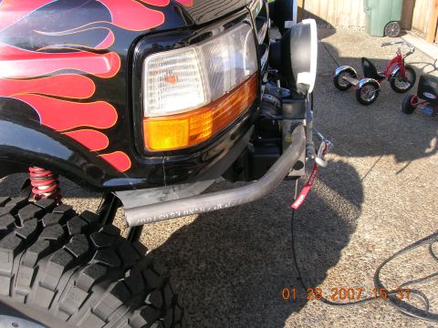 1996 Ford Bronco - A custom bumper is installed on a truck with flame decals and large off-road tires.