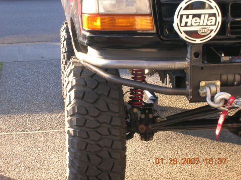 1996 Ford Bronco - Close-up of a modified Ford Bronco's front end, showing off-road suspension and bumper modifications.