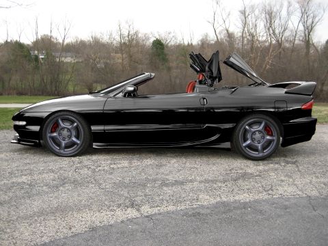 1995 Ford Probe - This 1995 Ford Probe convertible features a black exterior and a partially raised top, viewed from the side.