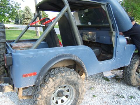 1980 Jeep CJ5 - This 1980 Jeep CJ5 features a roll cage, open hood, and off-road tires, suggesting it is being worked on or maintained.
