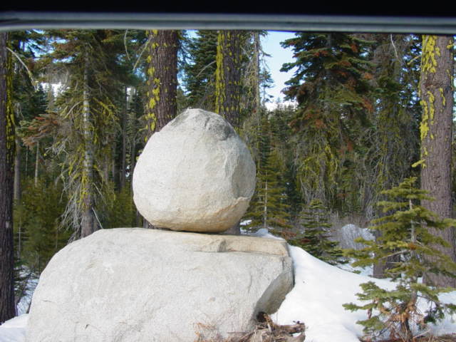 Balanced rocks in a snowy forest with pine trees