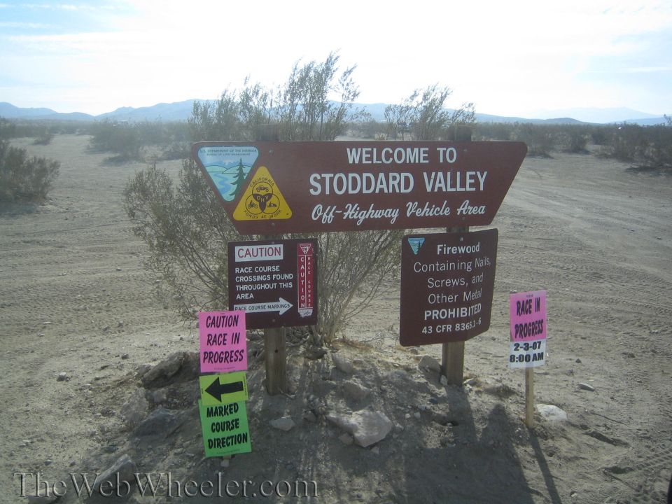 Brown 'Welcome to Stoddard Valley OHV Area' sign with race-in-progress placards