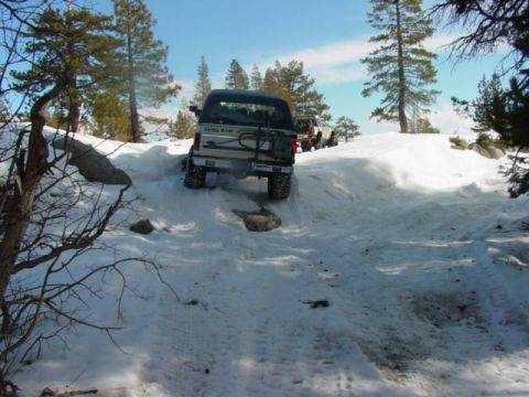 1986 Ford Bronco - A 1986 Ford Bronco navigates a snowy trail, with another vehicle visible behind it.
