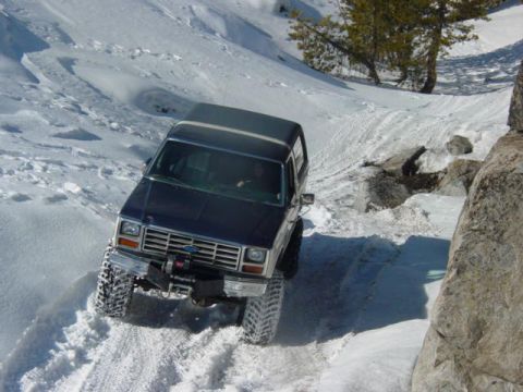 1986 Ford Bronco - A 1986 Ford Bronco navigates a treacherous snowy path on a mountain, its off-road capabilities.