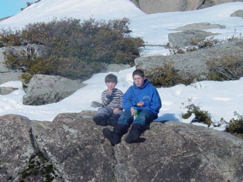 1986 Ford Bronco - Two boys take a break on rocks in a snowy, mountainous landscape.