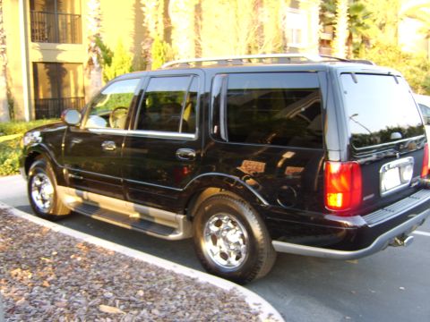 1996 Mercury Grand Marquis - A black full-size SUV parked in an outdoor lot, viewed from the rear driver's side (3/4 rear angle), with chrome five-spoke wheels, roof ra…
