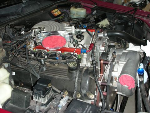 1992 Ford Crown Victoria - Close-up view of a modified engine bay a supercharger and prominent red fuel rails.