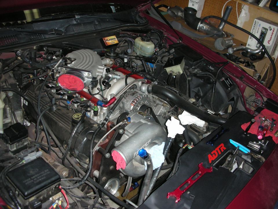 Engine bay with custom intake and intercooler piping. Tools are laid out on a black mat