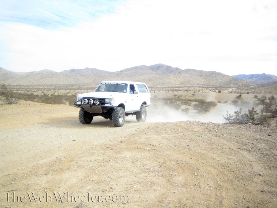 White lifted Ford Bronco-style SUV on a desert dirt road