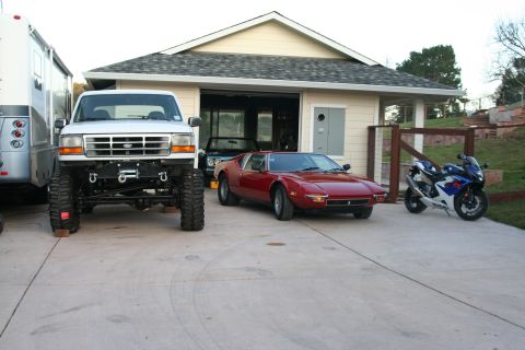 1992 Ford Bronco - A lifted 1992 Ford Bronco is parked in front of a garage, alongside a red sports car and a motorcycle.