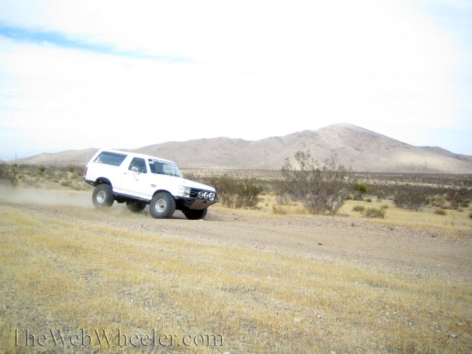 White lifted SUV cornering on a desert dirt road kicking up dust