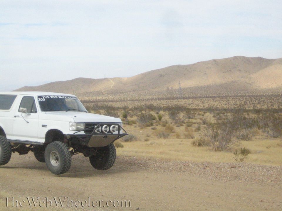 White lifted Bronco-style SUV with front light bar parked in desert