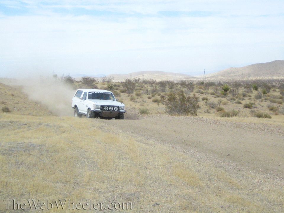 White lifted SUV cornering and raising dust on a desert trail