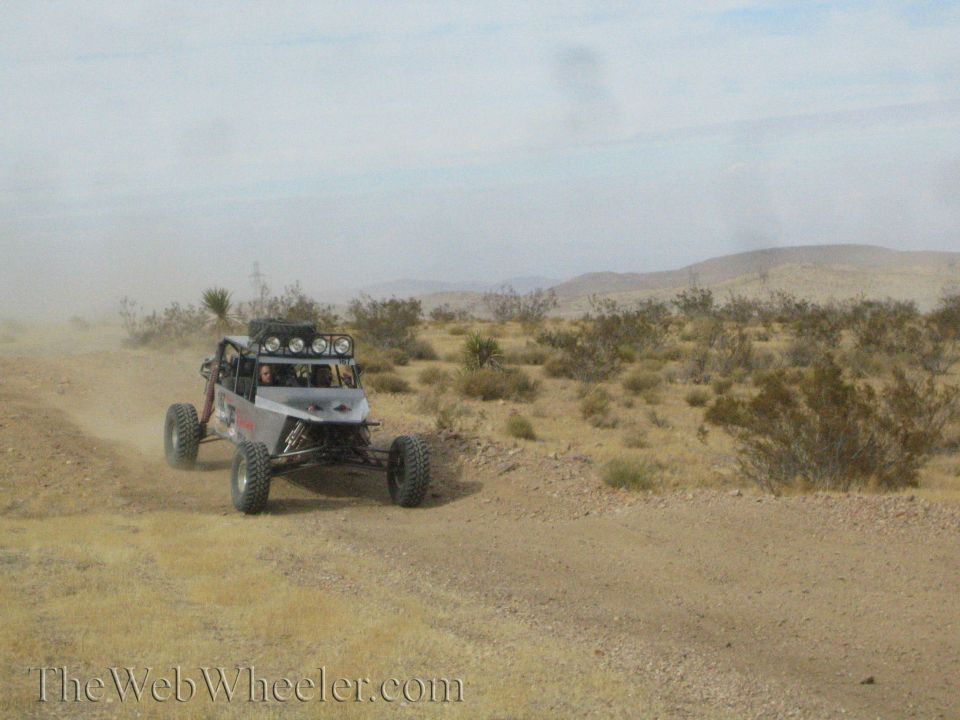 Off-road tube-frame race buggy cornering on a dusty desert trail