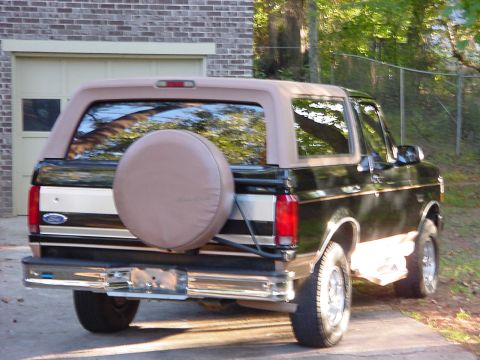 1994 Ford Bronco - This 1994 Ford Bronco is seen from the rear, a black body with tan accents and a spare tire mounted on the tailgate.