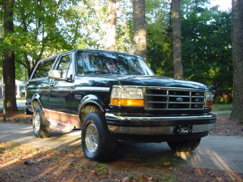 1994 Ford Bronco - Black 1994 Ford Bronco with wood paneling on the lower body, parked outdoors.