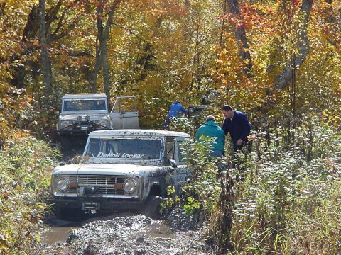 1994 Ford Bronco - Several Ford Broncos navigate a muddy trail during an off-road excursion in the fall.
