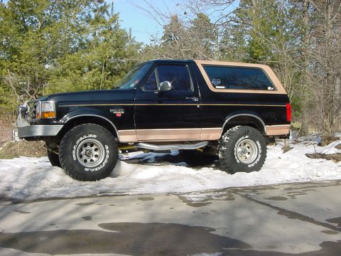 1994 Ford Bronco - Side view of a black 1994 Ford Bronco with tan trim, modified with aftermarket wheels and tires.