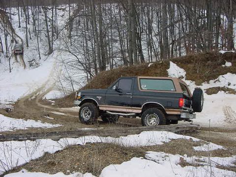 1994 Ford Bronco - This Ford Bronco navigates a muddy and snowy path through a forest.