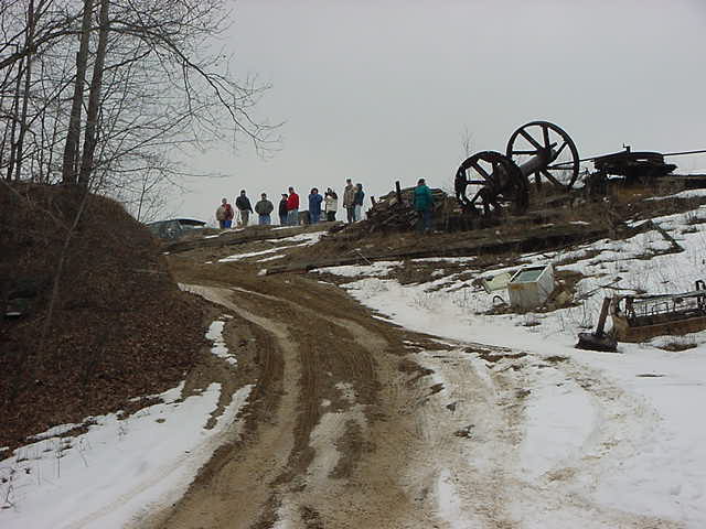 Dark SUV parked on a snowy hillside with a group of people standing nearby