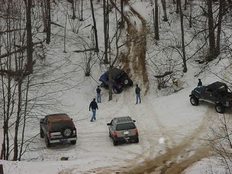 1994 Ford Bronco - Off-roading in snowy conditions proves challenging for multiple vehicles on a wooded trail.