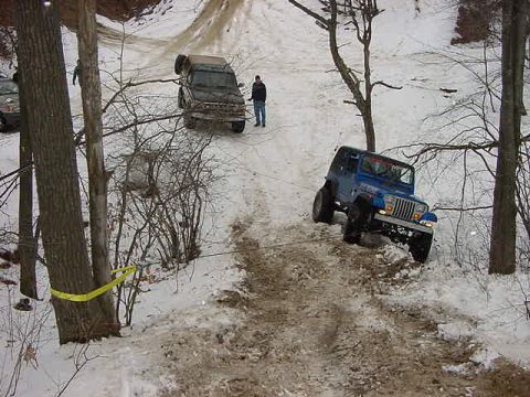 1994 Ford Bronco - Two off-road vehicles navigate a challenging snowy trail, with a blue Jeep Wrangler assisting a brown SUV.