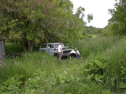 1994 Ford Bronco - Two people are working on the front of a 1978 Ford Bronco parked in tall grass.