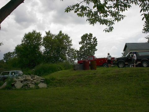 1994 Ford Bronco - A black Ford Bronco is parked on a grassy area next to a red pickup truck.