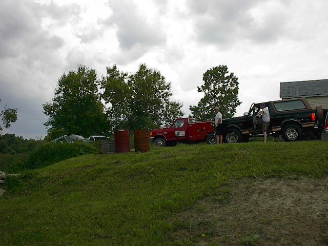 Black 1994 Ford Bronco with brown top, parked next to a red truck