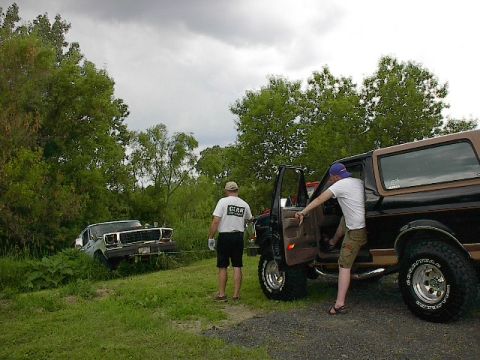 1994 Ford Bronco - Ford Bronco stuck in a ditch, with another Bronco attempting to pull it out.