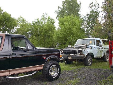 1994 Ford Bronco - Two Ford Broncos are parked outdoors, one in good condition and the other appearing to be a project vehicle inoperable project vehicle.