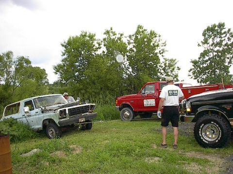 1994 Ford Bronco - A light blue SUV is being towed by a red truck, with a black truck also visible in the scene.
