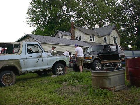1994 Ford Bronco - Two Ford Broncos are parked in a yard, one appears to be undergoing maintenance.