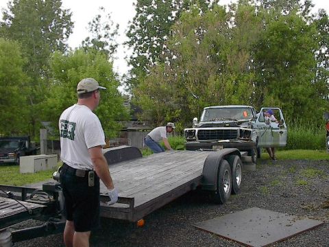 1994 Ford Bronco - A truck is being loaded onto a trailer by several people.
