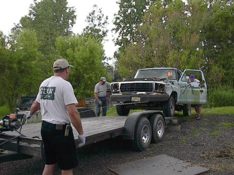 1994 Ford Bronco - A 1979 Ford F-Series truck is winched onto a trailer by two men.