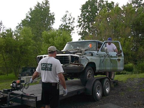 1994 Ford Bronco - Two men load a weathered pickup truck onto a trailer with a winch.