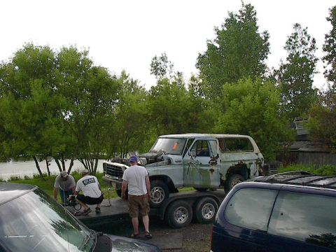 1994 Ford Bronco - A light blue Ford Bronco, likely from the late 1970s, is being loaded onto a trailer with assistance from three people.