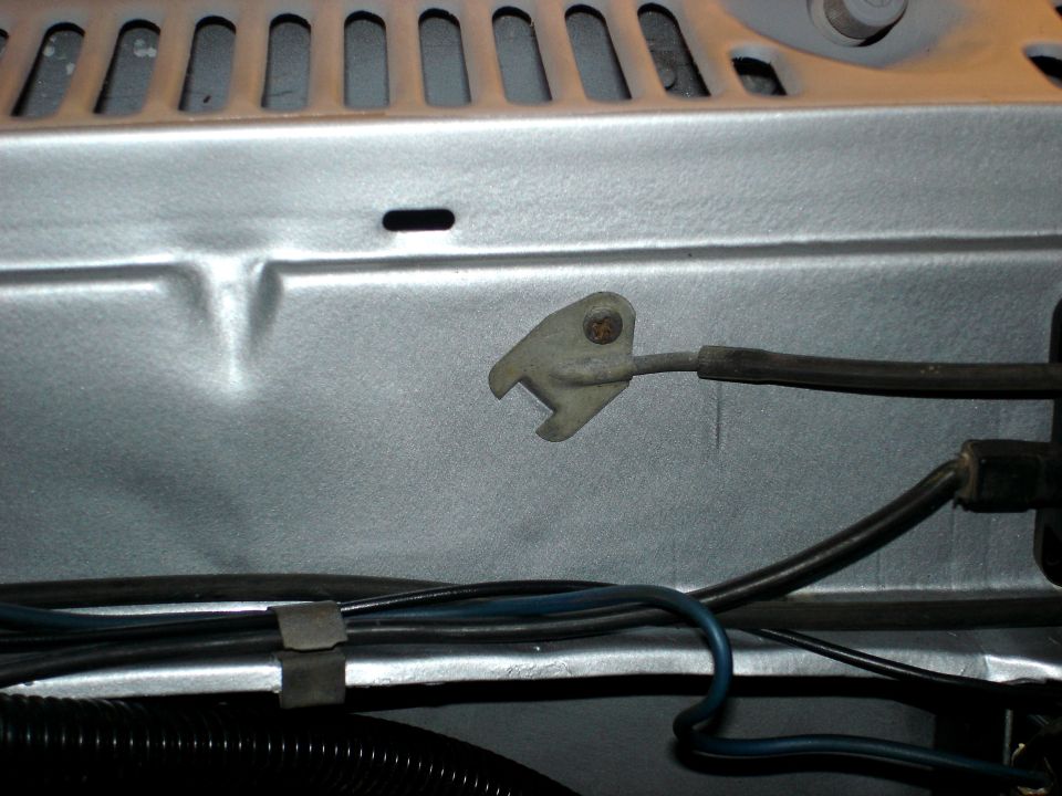Close-up of silver engine bay with wires and a metal clip. Supermotors.net logo visible