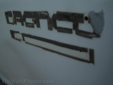 1990 Ford Bronco - Close-up of degraded, peeling decal residue and adhesive outline on a white painted body panel.